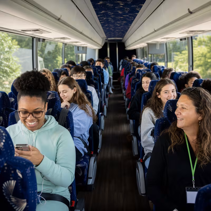 Group boarding a white charter bus for School Transportation transportation in San Francisco